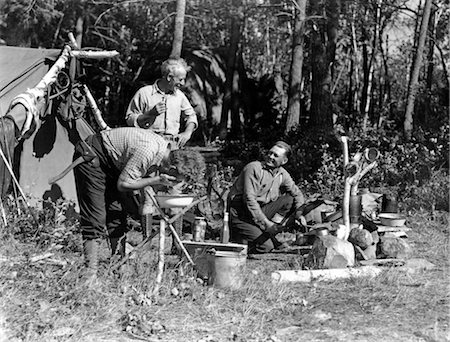 1940s MEN AT CAMPSITE ONE WASHING HIS FACE AT TRIPOD STAND THE OTHER TENDING CAMPFIRE CANADA LAKE OF THE WOODS ONTARIO Stock Photo - Rights-Managed, Code: 846-02792301