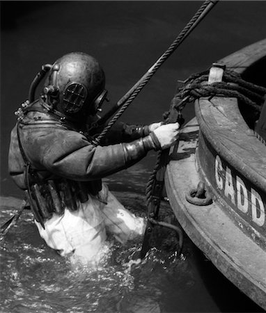 simsearch:846-02793819,k - 1930s SIDE VIEW OF DIVER IN PRESSURE SUIT DESCENDING INTO WATER FROM SIDE OF BOAT Stock Photo - Rights-Managed, Code: 846-02792355