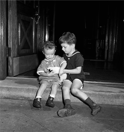 1940s 1950s TWO BOYS SITTING ON FRONT STEPS HOLDING A KITTEN Stock Photo - Rights-Managed, Code: 846-02792480