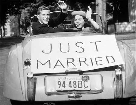 1950s NEWLYWED YOUNG COUPLE MAN WOMAN IN CONVERTIBLE SPORTS CAR WITH JUST MARRIED SIGN WAVING LOOKING AT CAMERA Stock Photo - Rights-Managed, Code: 846-02792516