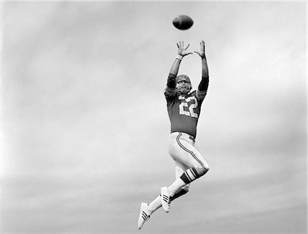 football ball american - 1970s PLAYER JUMPING TO CATCH FOOTBALL PASS Stock Photo - Rights-Managed, Code: 846-02792783