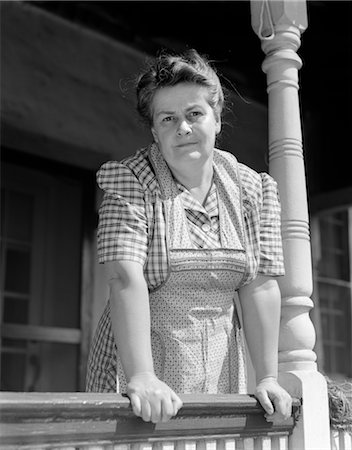 1940s OLDER WOMAN IN PLAID DRESS & APRON LEANING ON PORCH RAILING OF FARMHOUSE Stock Photo - Rights-Managed, Code: 846-02792879