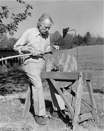 simsearch:846-02795969,k - 1940s ELDERLY MAN SEATED AT GRINDSTONE OUTDOORS SHARPEN TOOL AXE SHARP HONE TOOL WHETSTONE CUTTING EDGE FARMER TINKER Stock Photo - Rights-Managed, Code: 846-02792884
