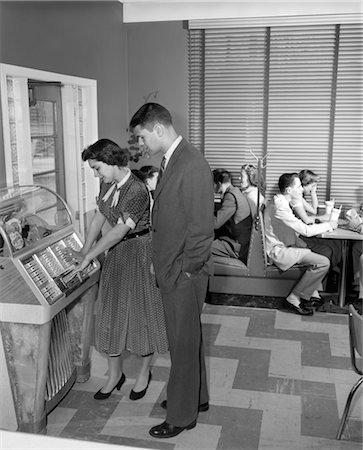 diner - 1950s TEEN CROWD SITTING IN BOOTHS WITH MALTS ONE COUPLE IN FOREGROUND ARE LOOKING AT JUKE BOX THE GIRL IS PLAYING IT INSIDE Stock Photo - Rights-Managed, Code: 846-02792904