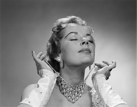 1950s WOMAN EYES CLOSED CHIN LIFTED PUTTING ON ELABORATE DIAMOND RHINESTONE NECKLACE Stock Photo - Rights-Managed, Code: 846-02793042