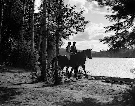 simsearch:846-02792220,k - 1930s MAN & WOMAN RIDING HORSES THROUGH WOODED AREA ALONG SIDE OF LAKE Stock Photo - Rights-Managed, Code: 846-02793162