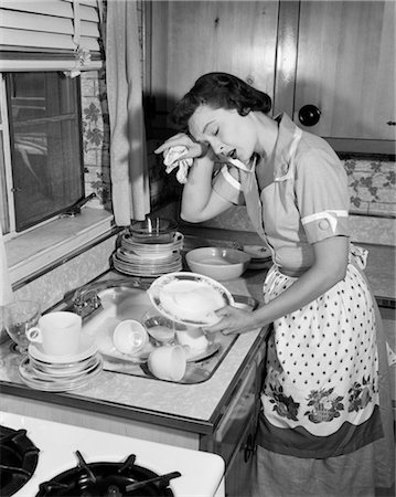 1950s TIRED EXHAUSTED WOMAN HOUSEWIFE IN KITCHEN WITH SINK FULL OF DIRTY DISHES Stock Photo - Rights-Managed, Code: 846-02793192