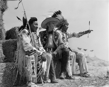simsearch:846-02792220,k - 1940s PAIR OF INDIANS IN FULL COSTUME SITTING ON BALES OF HAY WITH COWBOY BETWEEN THEM Stock Photo - Rights-Managed, Code: 846-02793345