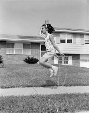 simsearch:846-02797740,k - 1960s GIRL JUMPING ROPE ON SIDEWALK JUMP IN FRONT OF HOUSE WEAR SUMMER SHORTS SNEAKERS FUN FIT EXERCISE PLAY Stock Photo - Rights-Managed, Code: 846-02793487