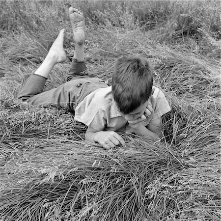 1960s BAREFOOT BOY LYING STOMACH-DOWN RUNNING FINGERS THROUGH HIGH GRASS Stock Photo - Rights-Managed, Code: 846-02793497