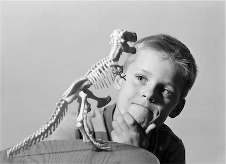 1960s BLOND BOY HAND ON CHIN LOOKING AT SKELETON MODEL OF DINOSAUR TYRANNOSAURUS REX Stock Photo - Rights-Managed, Code: 846-02793491