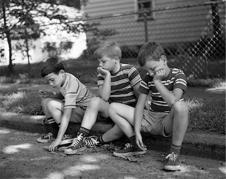 1970s THREE BORED BOYS SITTING ON CURB ALL WEARING STRIPED TEE SHIRTS SHORTS AND SNEAKERS Stock Photo - Rights-Managed, Code: 846-02793520