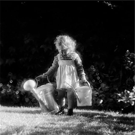 1930s 1940s CUTE LITTLE BLOND GIRL IN PINAFORE HOLDING TWO WATERING CANS WALKING IN BACKYARD Stock Photo - Rights-Managed, Code: 846-02793544