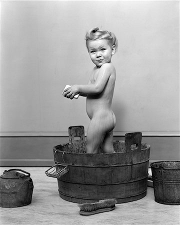 1940s LITTLE BLOND GIRL STANDING IN WOODEN WASHTUB HOLDING BAR OF SOAP TAKING A BATH Stock Photo - Rights-Managed, Code: 846-02793658