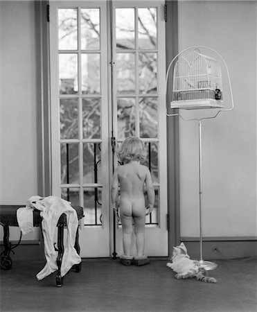 simsearch:846-02797888,k - 1950s YOUNG GIRL NUDE BACK TO CAMERA FACING OUT WINDOW CLOTHES BESIDE HER CAT AND BIRD IN BIRDCAGE NEXT TO HER Stock Photo - Rights-Managed, Code: 846-02793652