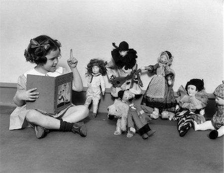 1930s LITTLE GIRL POINTING A FINGER READING BOOK TO A ROW OF DOLLS TOYS STUFFED ANIMALS Stock Photo - Rights-Managed, Code: 846-02793766