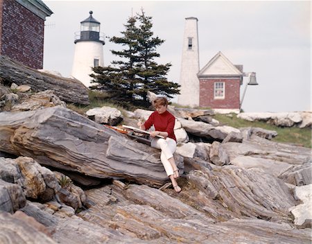 sentinel - 1960s 1970s RETRO ARTIST PAINTER WOMAN PAINTING NEW HARBOR PEMAQUID MAINE LIGHTHOUSE AND ROCK FORMATIONS Stock Photo - Rights-Managed, Code: 846-02793842