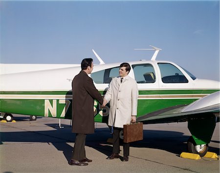 1960s 2 SALESMEN SHAKING HANDS STAND ON TARMAC BY PRIVATE PLANE BRIEFCASE OVERCOAT Stock Photo - Rights-Managed, Code: 846-02793843