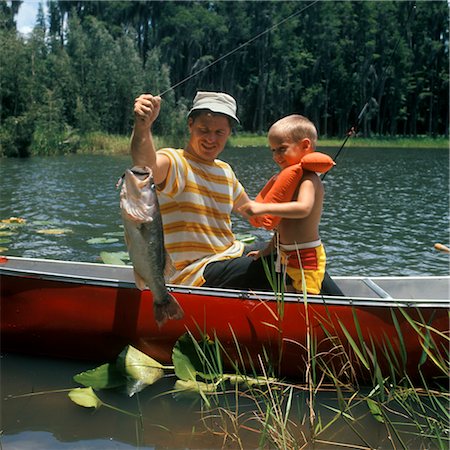 retro fishing - 1980s FATHER & SON IN CANOE HOLDING UP CATCH FISH LAKE BOY LIFE PRESERVER FISHING MAN MEN FAMILY ACTIVITY Stock Photo - Rights-Managed, Code: 846-02793861