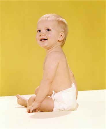 1970s SMILING BABY WEARING DIAPER SITTING ON BLANKET LOOKING OVER SHOULDER Stock Photo - Rights-Managed, Code: 846-02793917