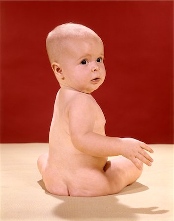 1960s NAKED BABY SITTING ON YELLOW BLANKET LOOKING OVER SHOULDER Stock Photo - Rights-Managed, Code: 846-02793996