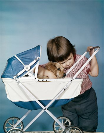 spaniel - 1950s 1960s LITTLE GIRL HUGGING COCKER SPANIEL PUPPY RIDING IN A BABY CARRIAGE STUDIO Stock Photo - Rights-Managed, Code: 846-03164099