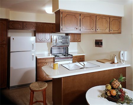 1960s KITCHEN INTERIOR WITH BROWN CABINETS AND WHITE COUNTER ISLAND WITH SINK Stock Photo - Rights-Managed, Code: 846-03164790
