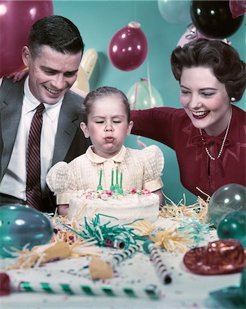 1950s MOTHER FATHER DAUGHTER BLOWING OUT CANDLES ON BIRTHDAY CAKE Stock Photo - Rights-Managed, Code: 846-03164864