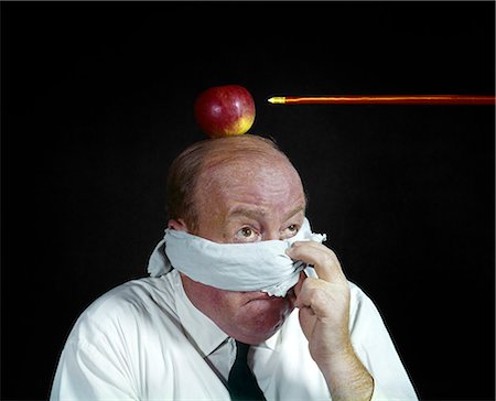 1960s ANXIOUS MAN PEEKING FROM BLINDFOLD TO ARROW DIRECTED AT APPLE TOP HIS HEAD TARGET WILLIAM TELL BUSINESSMAN Stock Photo - Rights-Managed, Code: 846-03165232