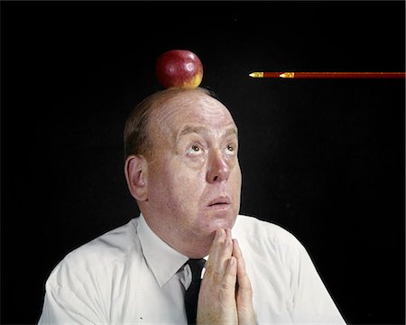 1960s ANXIOUS BUSINESS MAN PRAYING LOOKING UP AT ARROW DIRECTED APPLE TOP HEAD SYMBOLIC WILLIAM TELL Stock Photo - Rights-Managed, Code: 846-03165233