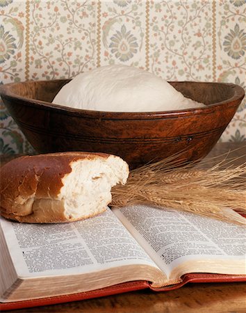 STILL LIFE OF BREAD DOUGH IN BOWL A LOAF OF BREAD AND WHEAT STALKS ON AN OPEN BIBLE Stock Photo - Rights-Managed, Code: 846-03165636