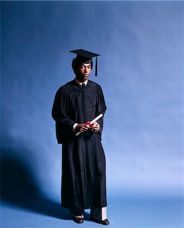 1970s FULL LENGTH PORTRAIT AFRICAN AMERICAN YOUNG MAN SCHOOL GRADUATE BLACK CAP GOWN HOLDING DIPLOMA Stock Photo - Rights-Managed, Code: 846-03165812