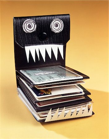 1960s SYMBOLIC MONSTER WALLET WITH WILD EYES AND SHARP TEETH FILLED WITH CREDIT CARDS Stock Photo - Rights-Managed, Code: 846-03166041