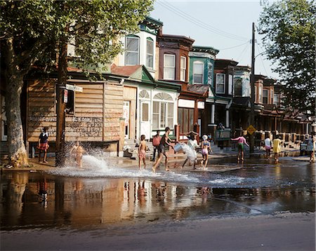 1970s CHILDREN IN URBAN NEIGHBORHOOD PLAYING IN STREET IN WATER SPRAY FROM HYDRANT Stock Photo - Rights-Managed, Code: 846-03166185