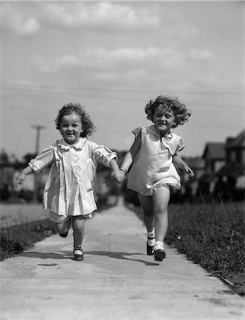 1930s TWO CHILDREN RUNNING SKIPPING ON SIDEWALK SMILING Stock Photo - Rights-Managed, Code: 846-03163480