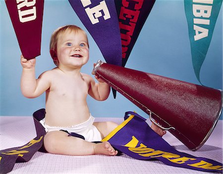1960s SMILING HAPPY BABY WITH COLLEGE PENNANTS HOLDING CHEERLEADER MEGAPHONE Stock Photo - Rights-Managed, Code: 846-03163951