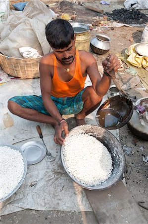 Man in vest and dhoti pouring sugar syrup onto bowl of puffed rice to make prasad, Sonepur Cattle Fair, Bihar, India, Asia Stock Photo - Rights-Managed, Code: 841-06343892