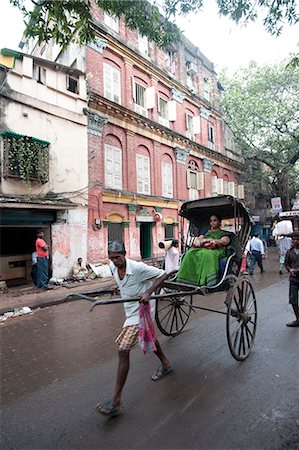 Woman riding in running rickshaw passing beautiful old Raj era Kolkata building in Kolkata backstreet, West Bengal, India, Asia Stock Photo - Rights-Managed, Code: 841-06447748