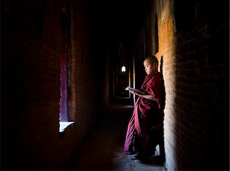 Novice Buddhist monk reading Buddhist scriptures in the light of a window in one of the many temples of Bagan, Myanmar (Burma), Asia Stock Photo - Rights-Managed, Code: 841-06805729