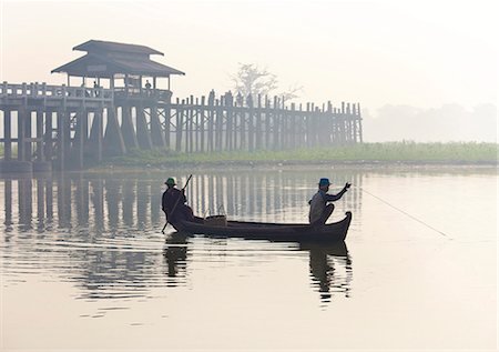 side view of person rowing in boat - Fisherman on Taungthaman Lake in mist at dawn with U Bein Bridge, the world's longest teak foot bridge spanning 1300 yards, Amarapura, near Mandalay, Myanmar (Burma), Asia Stock Photo - Rights-Managed, Code: 841-07081628