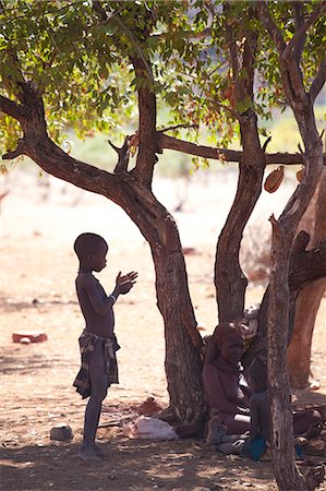 simsearch:841-06342689,k - Young Himba boy standing in the shade of a tree in semi-silhouette, Kunene Region (formerly Kaokoland) in the far north of Namibia Stock Photo - Rights-Managed, Code: 841-07081784