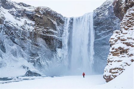 polar region - One person in red jacket walking in the snow towards Skogafoss waterfall in winter, Skogar, South Iceland, Iceland, Polar Regions Stock Photo - Rights-Managed, Code: 841-08101836