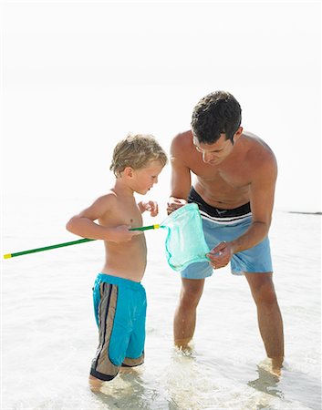 Father and son (6-8) in the surf holding fishing pole Stock Photo - Rights-Managed, Code: 841-02720363