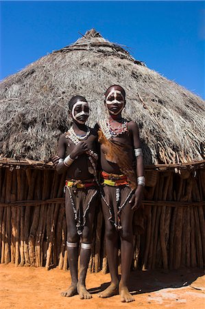 Hamer girls standing in front of house, wearing traditional goat skin dress decorated with cowie shells, Dombo village, Turmi, Lower Omo valley, Ethiopia, Africa Stock Photo - Rights-Managed, Code: 841-02916988