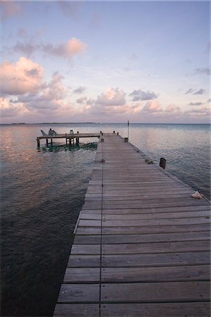 People sitting on chair on jetty at sunrise, Tobaco Caye, Belize, Central America Stock Photo - Rights-Managed, Code: 841-02917464