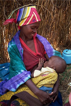 refugee - Portrait of a Rwandan refugee woman in traditional clothing, sitting on the ground breastfeeding her baby, Tanzania, East Africa, Africa Stock Photo - Rights-Managed, Code: 841-02947184