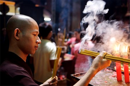 Monk lighting joss sticks during ceremony in a Buddhist temple, Ho Chi Min City, Vietnam, Indochina, Southeast Asia, Asia&#10; Stock Photo - Rights-Managed, Code: 841-03870741