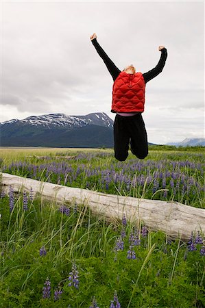 picture of orange and green object - Female hiker jumping off of log in field of lupine Turnagain Arm Southcentral Alaska Summer Stock Photo - Rights-Managed, Code: 854-02955231