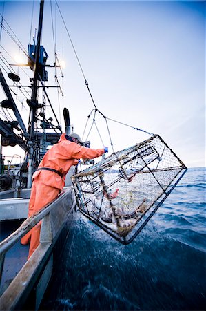 Deckhands lower a baited pot over the deck of the F/V Centurion while cod fishing in Kachemak Bay, Alaska Stock Photo - Rights-Managed, Code: 854-03538522