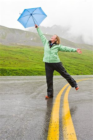 shower kid - Woman walking down the middle of a road and joyfully holds an umbrella in her outstreched hand in Alaska during Summer Stock Photo - Rights-Managed, Code: 854-03539080